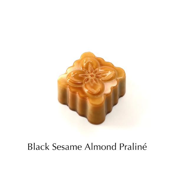 An image of Formosa's Black Sesame Almond Praline chocolate bonbon. The product is shaped to look like a traditional moon cake.