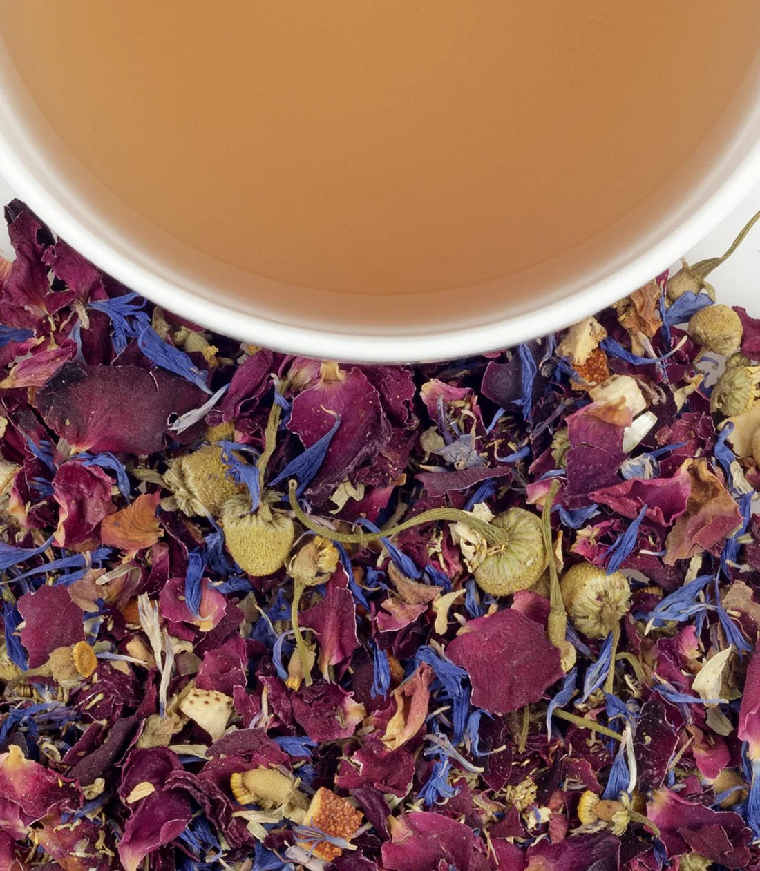 A close up photograph of Harney & Sons Mother's Day tea dried flowers and a cropped cup with the brewed tea inside to show the color.