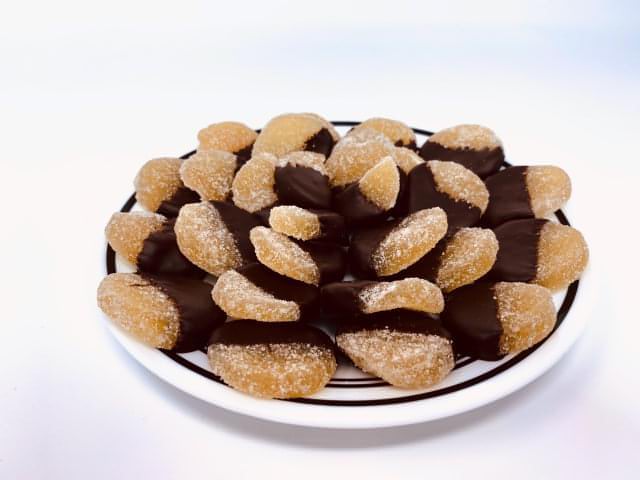 A plate of Formosa brand dark chocolate covered candied ginger pieces on a white background.
