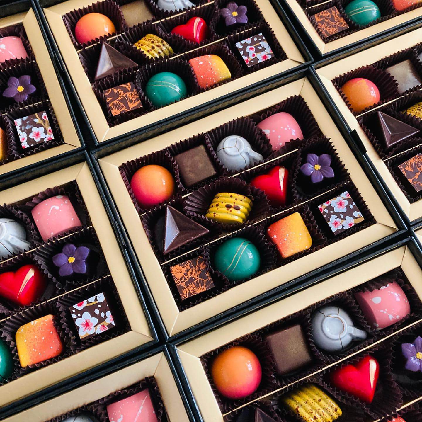 A close up view of multiple open boxes of Formosa Fine Chocolates with various colorful chocolates placed together.
