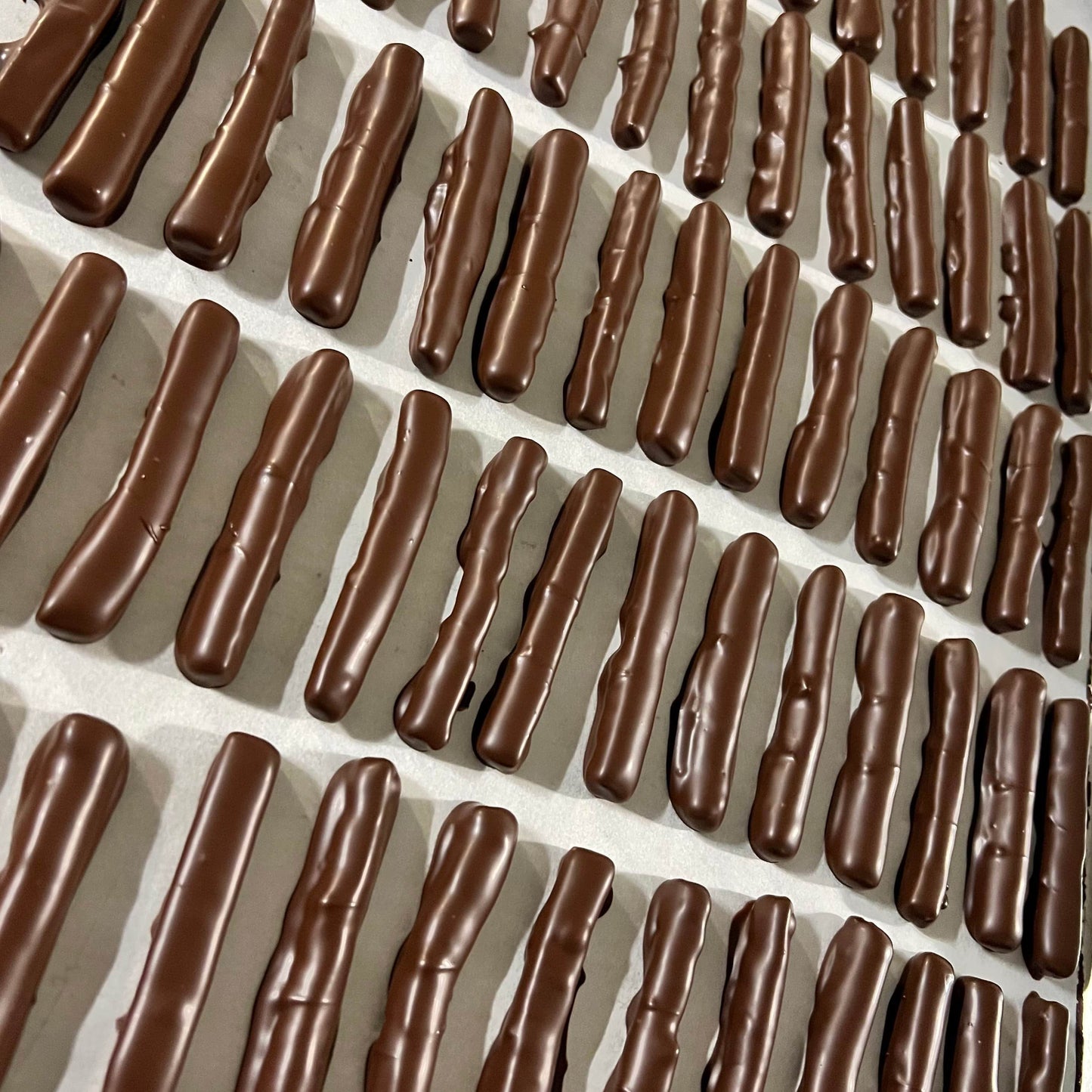 A close up shot of Formosa brand candied orange chocolate sticks arranged in a decorative pattern on a white surface.