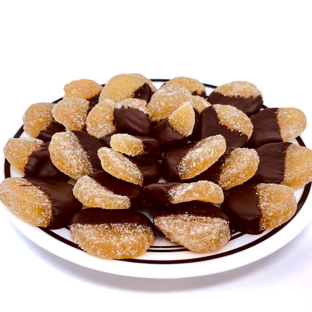 Plate of chocolate-dipped candied ginger pieces on a white background