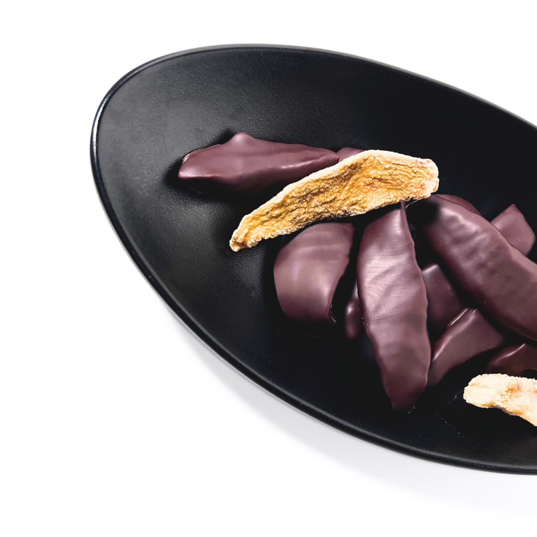 a photo of a handful of dried Taiwanese pearl guava, two of which are just the dried guava and the rest are enrobed in dark chocolate made by Formosa, and displayed in a decorative black bowl on a white background. 