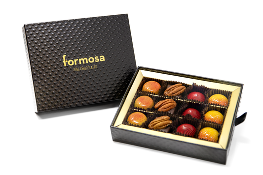 The 2025 Formosa Chocolate's Harvest collection twelve piece box displayed open showing all the bonbons set against a white background. 